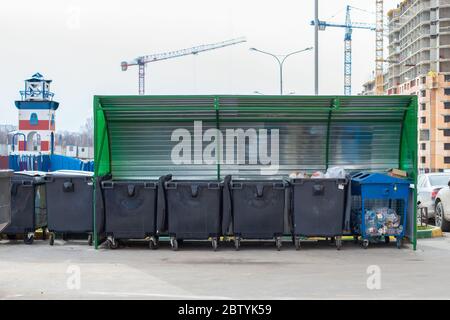Lots of black plastic trash containers, residential area new building. Garbage sorting, environmental problems pollution. Trash can on wheels, generat Stock Photo