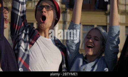 Happy young friends put hands on top of each other. Great team w Stock Photo