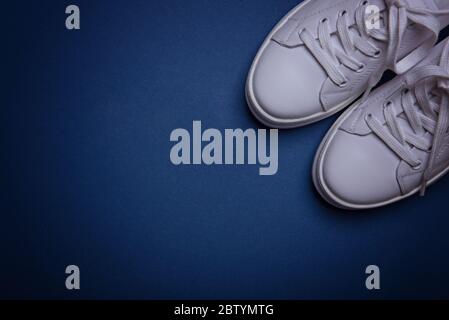 White sneakers on the classic blue background. Flat lay. Copy space. Place for text. Abstract surrealism and minimalism shopping concept. Stock Photo