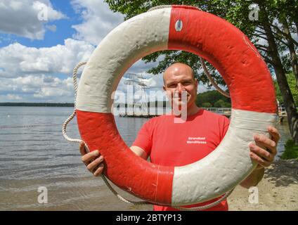 Wandlitz, Germany. 28th May, 2020. Dennis Kowald, head of the lido at Strandbad Wandlitzsee, looks through a lifebelt and is looking forward to the first visitors. Iin the bath in the district of Barnim, world war ammunition was detonated for the last time on 26.05.2020. For two years, professional divers had been looking for explosive ordnance in the lake. From 29.05.2020 the lido is open again. Credit: Patrick Pleul/dpa-Zentralbild/ZB/dpa/Alamy Live News Stock Photo