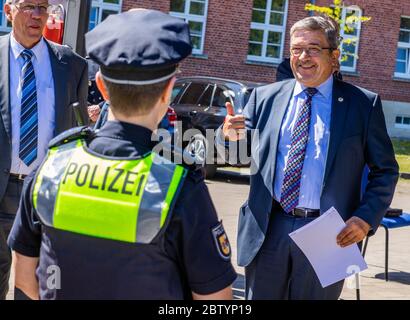 28 May 2020, Mecklenburg-Western Pomerania, Schwerin: Lorenz Caffier (CDU - r), the Minister of the Interior of Mecklenburg-Vorpommern, talks to a police officer wearing the new overt vest for equipment. The so-called 'outer carrying case' is a vest that provides additional protection for police officers and makes it easier to store equipment. Police officers have contributed to the development of the new model with their practical experience. Photo: Jens Büttner/dpa-Zentralbild/dpa Stock Photo