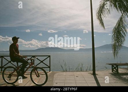 Local Resident Rides a Bicycle on the Lake Chapala Malecon Waterfront in Chapala Town, Jalisco, Mexico Stock Photo