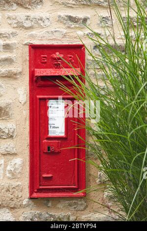 Traditional red post box on stone wall, Burford, Cotswolds, England, UK Stock Photo
