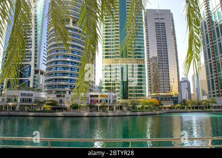 Dubai / UAE - May 26, 2020: View of Jumeirah Lakes Towers district. View of JLT district through palms foliage on a foreground. Stock Photo
