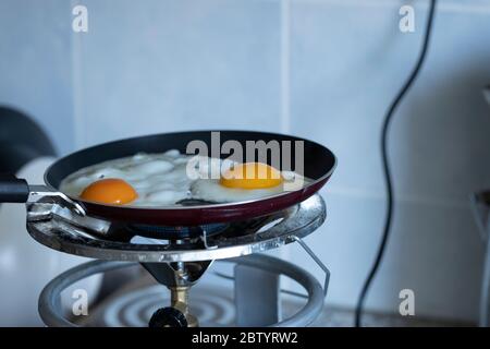 2 scrambled eggs on the pan. On the gas cylinder. Close up. Stock Photo