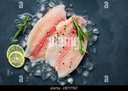 Fresh fish fillet of sea bass in ice on a dark slate background. Top view. Stock Photo