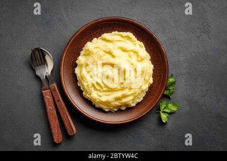 Mashed potatoes, boiled puree in a brown plate on a black slate background. Top view. Flat lay. Stock Photo