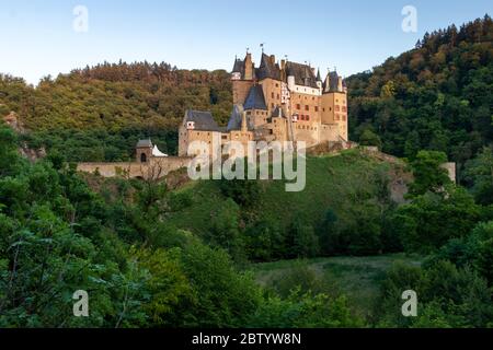 Burg Eltz, a castle in Germany, in a valley surrounded by green trees on a spring day. Stock Photo