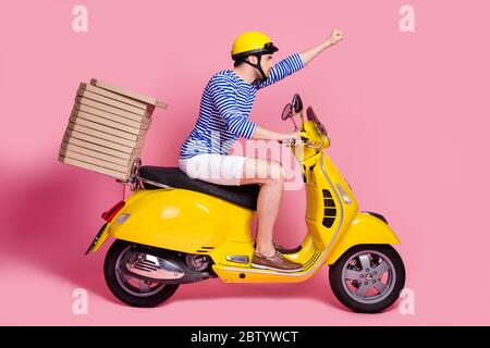 Profile side view of his he nice attractive handsome cool confident guy driving moped delivering pizza fast service hurry rush isolated over pink Stock Photo