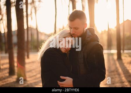 Young happy couple in love romancing while standing in park at sunset Stock Photo