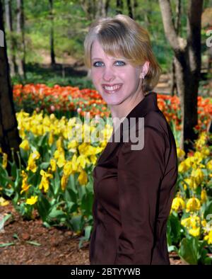 Beautiful young woman explores the tulips at Garvan Woodland Garden in Hot Springs, Arkansas.  She is smiling and happy. Stock Photo