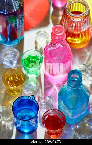 Colourful bottles and glasses, ice cubes Stock Photo
