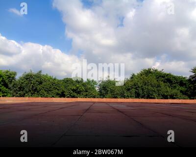 Blue dramatic cloudy sky trees and red marble floor Stock Photo
