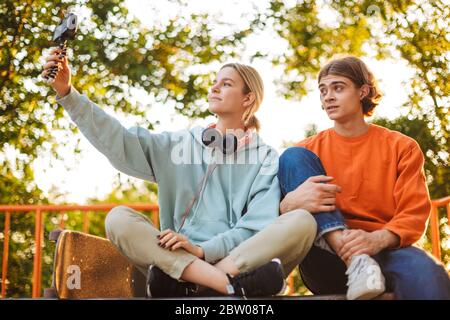 Young skater boy and girl recording new video while spending time together at skatepark Stock Photo