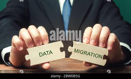 Businessman collects wooden puzzles with the words Data migration. Process of preparing, selecting, extracting data and transferring from one computer Stock Photo