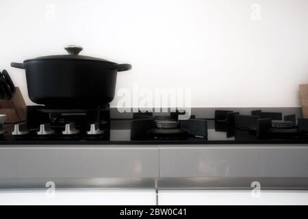 Cooking on a gas stove with a black modern iron casserole pan retro design Stock Photo