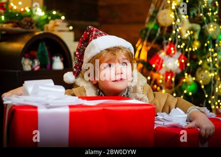 Happy child holding a giant red gift box with both hands. Christmas kids. New year kids. Funny kid holding Christmas gift Stock Photo