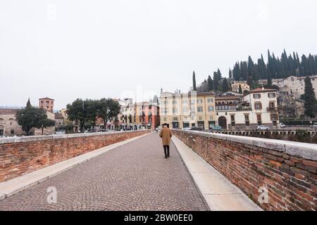 VERONA, ITALY - 14, MARCH, 2018: Horizontal picture of pedestrian crossing Ponte Pietra, a famous bridge of Verona, Italy Stock Photo