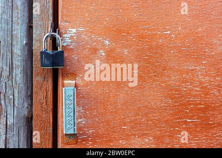 Old padlock iron lock on an old door with peeling paint. Stock Photo