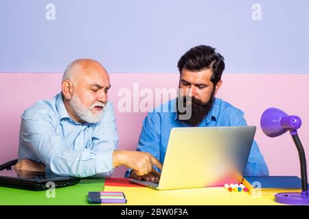 World teachers day. Happy Son and Grandfather sitting at a desk indoors. Educational process. Grandfather with Son learning together Stock Photo