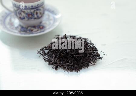 dry black tea and mug with tea. some sort of dried tea in studio, with white cup and tea pot Stock Photo