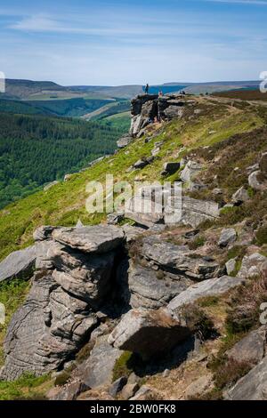 View from Bamford Edge toward Ladybower Reservoir with people sitting/climbing/ enjoying the day after coronavirus lockdown has been eased Stock Photo