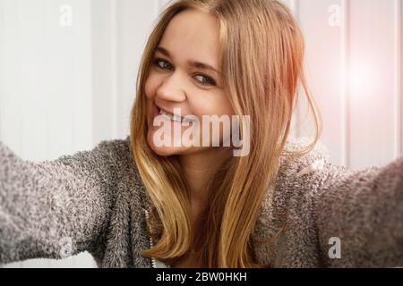 Picture of young happy emotional pretty lady indoors. Looking camera make selfie Stock Photo