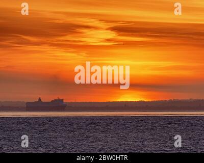 Sheerness, Kent, UK. 28th May, 2020. UK Weather: shipping on the Thames passes the sunset as seen from Sheerness in Kent. Credit: James Bell/Alamy Live News Stock Photo