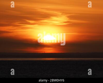 Sheerness, Kent, UK. 28th May, 2020. UK Weather: shipping on the Thames passes the sunset as seen from Sheerness in Kent. Credit: James Bell/Alamy Live News Stock Photo