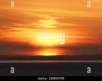 Sheerness, Kent, UK. 28th May, 2020. UK Weather: shipping on the Thames passes the sunset as seen from Sheerness in Kent. Credit: James Bell/Alamy Live News Stock Photo