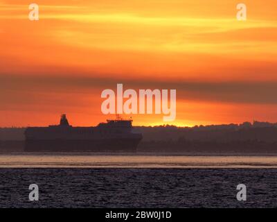 Sheerness, Kent, UK. 28th May, 2020. UK Weather: shipping on the Thames passes the sunset as seen from Sheerness in Kent. Credit: James Bell/Alamy Live News Stock Photo