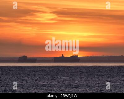 Sheerness, Kent, UK. 28th May, 2020. UK Weather: shipping on the Thames passes the sunset as seen from Sheerness in Kent. Credit: James Bell/Alamy Live News Stock Photo