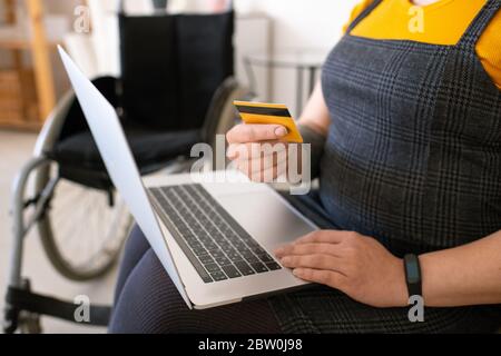 Close-up of unrecognizable disabled woman using laptop while paying with credit card online Stock Photo