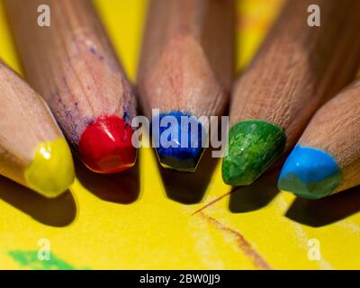 Closeup of five colored yellow, red, blue, green and light blue pencils of my children on a yellow paper Stock Photo