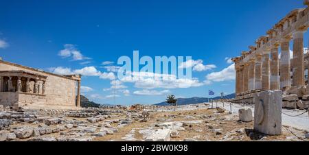 Athens Acropolis, Greece. Parthenon temple and part of Erechtheum, greek flag waving against blue sky background, spring sunny day. Stock Photo