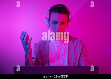 Gamer plays on a laptop. The programmer writes the code. Man on a colored background Stock Photo