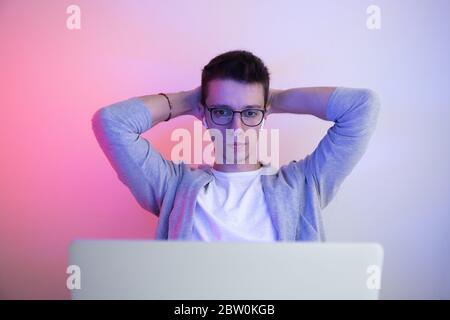 Gamer plays on a laptop. The programmer writes the code. Man on a colored background Stock Photo