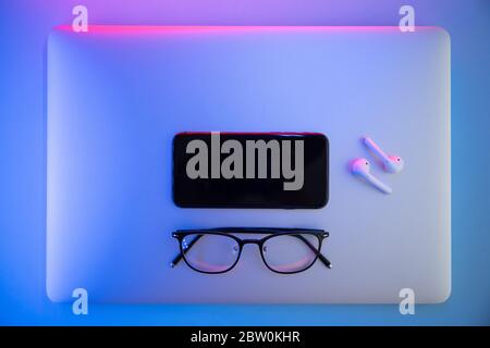 On a colored background, Laptop, glasses, pen, headphones, top view. Business concept Stock Photo