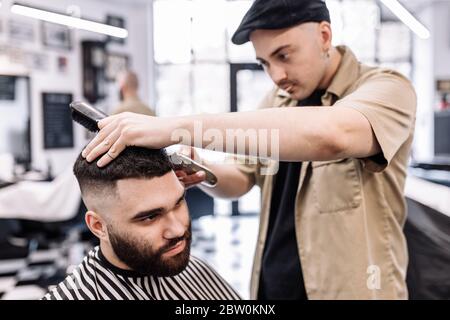 Classic haircut in a barbershop. Curve hair styling and hair health care in a barbershop.  Stock Photo