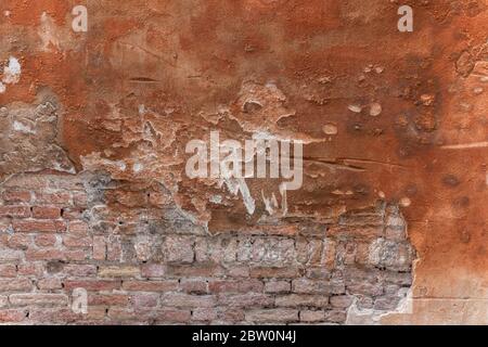 Unfinished red plastered wall with bricks showing through Stock Photo