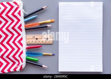 Lined paper on table beside pencil case full of stationery supplies Stock Photo