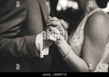 Black and white photo on dancing pair in formal clothes. Close up of holding hands. Shallow depth of field. Stock Photo
