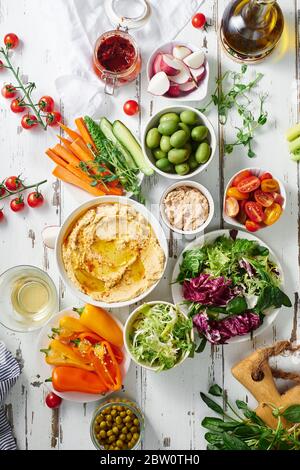 Flatlay with two dips and raw vegetarian snacks on white wooden table. Stock Photo