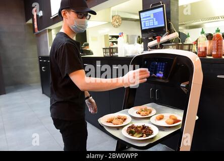 Vienna, Austria. 28th May, 2020. A waiter sets the table number for the robot delivery at an Asian restaurant in Vienna, Austria, on May 28, 2020. An Asian restaurant in Vienna uses robots to deliver meals in order to reduce unnecessary contact between waiters and customers during the COVID-19 outbreak. Credit: Guo Chen/Xinhua/Alamy Live News Stock Photo