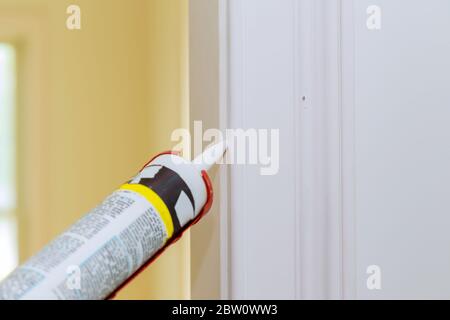 Hands of worker using a silicone tube for repairing of molding door trim Stock Photo