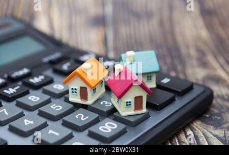 Buy home. House is placed on the calculator. Planning savings money of coins to buy a home concept for property, mortgage and real estate investment. Stock Photo