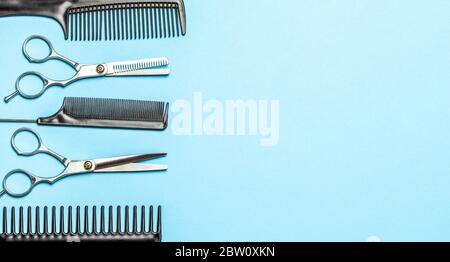 Black combs and combs with scissors on blue background. Copy space for text Stock Photo