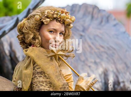 Saint John, New Brunswick, Canada - July 13, 2017: Buskers Festival. A woman dressed as a fairy, completely in gold and with gold makeup, with a wand. Stock Photo