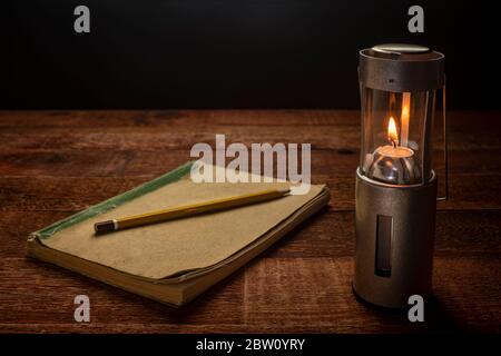 collapsible camping candle lantern burning in darkness on a rustic