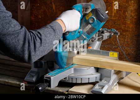 Closeup of professional cabinet makers working with electric circular saw at woodworking workshop. Wood material production. Lumber factory Stock Photo